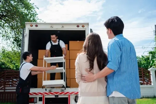 Operarios cargando un camión de transporte bajo la supervisión de clientes en un servicio de mudanza de oficina.